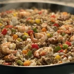 Cajun Seafood Dirty Rice Skillet with shrimp, crab, sausage, peppers, and buttery seasoned rice in a cast-iron pan.