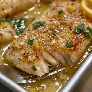 Lemon garlic butter fish fillets served with lemon slices, parsley, and glossy butter sauce.